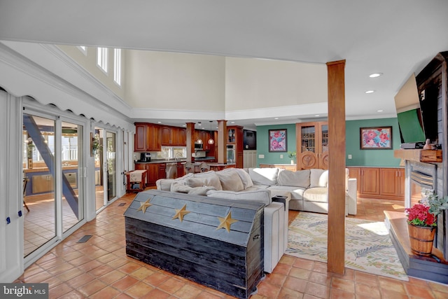 tiled living room with ornamental molding and a high ceiling