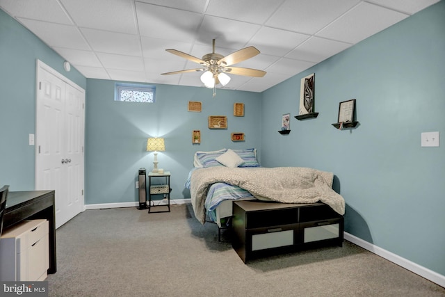 bedroom with a drop ceiling, a closet, carpet flooring, and ceiling fan