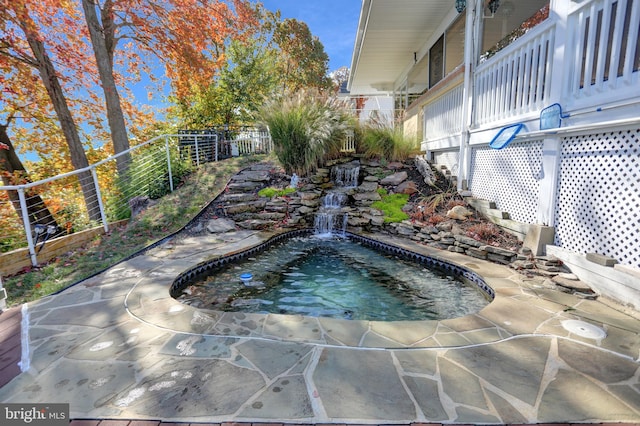 view of swimming pool with pool water feature and a patio