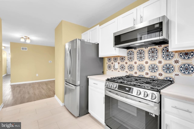 kitchen featuring stainless steel appliances, tasteful backsplash, light wood-type flooring, and white cabinets