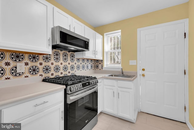 kitchen with white cabinetry, backsplash, stainless steel appliances, and sink