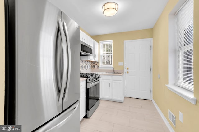 kitchen with sink, white cabinetry, decorative backsplash, and stainless steel appliances