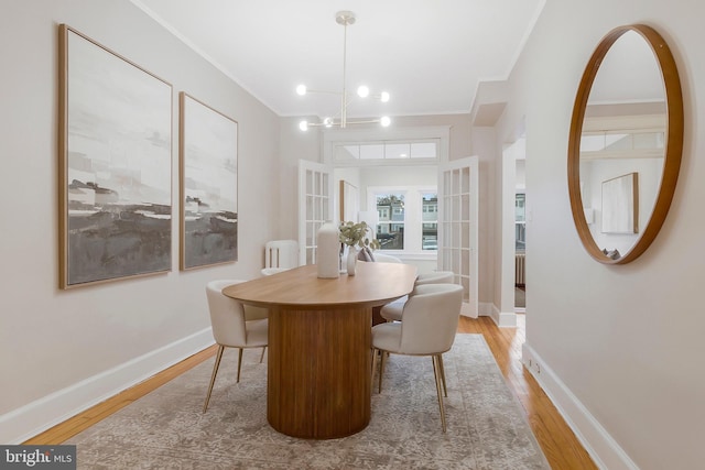 dining space with an inviting chandelier, light hardwood / wood-style flooring, and crown molding