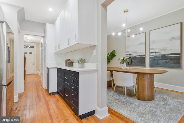 kitchen featuring stainless steel fridge with ice dispenser, pendant lighting, white cabinetry, and light hardwood / wood-style flooring