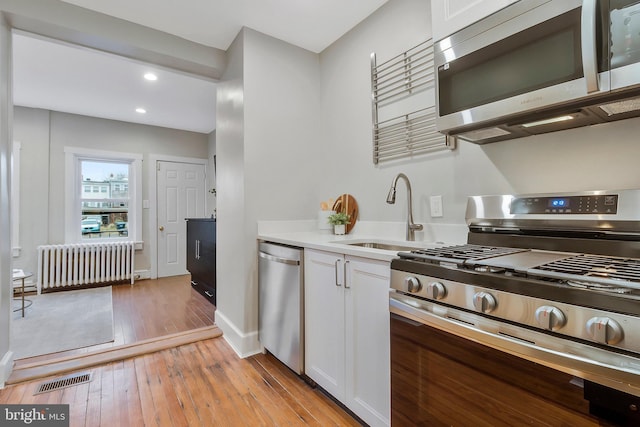 213 Channing St NE, Washington, DC 20002 - kitchen with stainless steel appliances, radiator, white cabinetry, light countertops, and recessed lighting