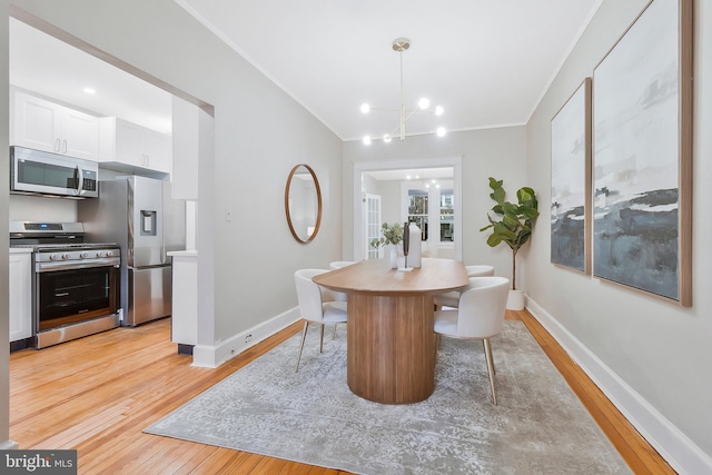 dining space with light hardwood / wood-style floors, an inviting chandelier, and crown molding