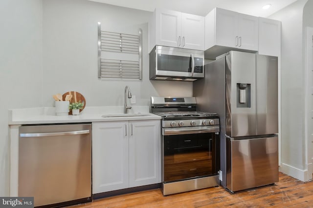 kitchen featuring appliances with stainless steel finishes, light hardwood / wood-style floors, white cabinetry, and sink