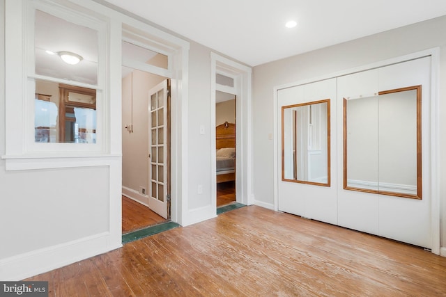 unfurnished bedroom with light wood-type flooring, white refrigerator, and a closet