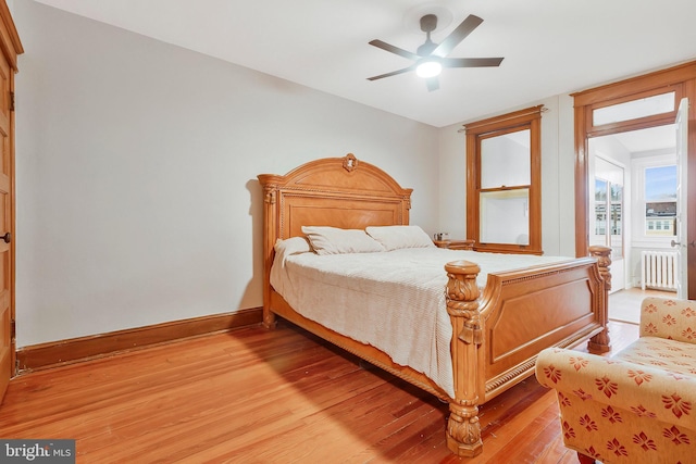 bedroom featuring radiator heating unit, light hardwood / wood-style flooring, and ceiling fan