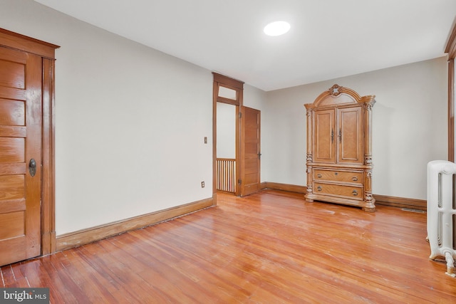 unfurnished bedroom with light hardwood / wood-style flooring and radiator heating unit