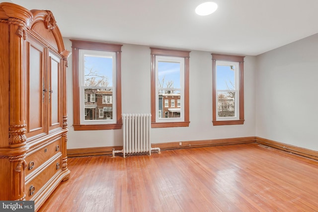 unfurnished room featuring radiator heating unit, a healthy amount of sunlight, and light wood-type flooring