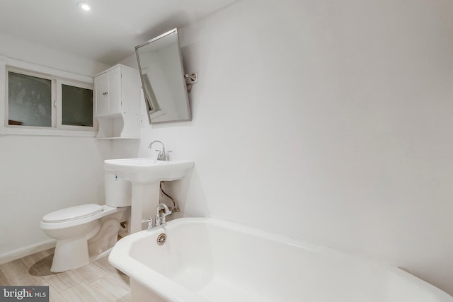 bathroom featuring toilet, wood-type flooring, and a tub to relax in