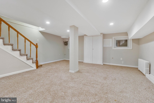 basement featuring light colored carpet and radiator