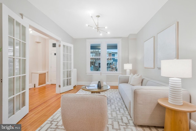 living room featuring french doors, light wood-type flooring, and an inviting chandelier