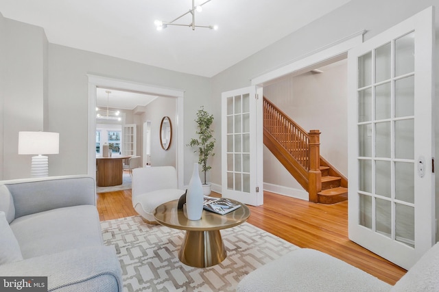 living room with french doors, hardwood / wood-style flooring, and an inviting chandelier