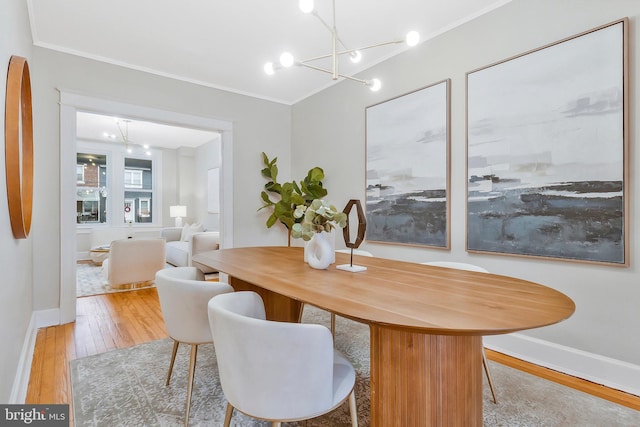 dining space with light hardwood / wood-style floors, an inviting chandelier, and crown molding