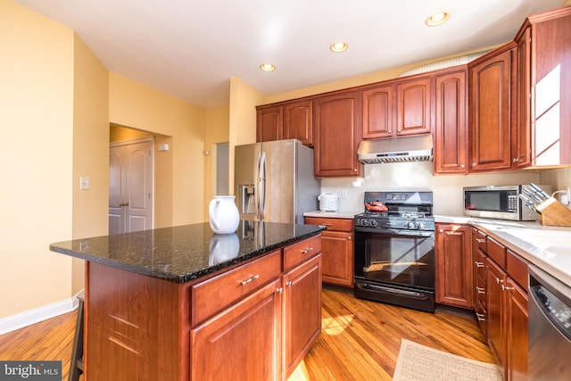 kitchen with a kitchen island, a breakfast bar, dark stone counters, light hardwood / wood-style floors, and stainless steel appliances