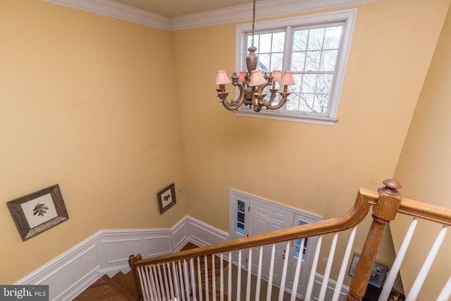 stairway featuring an inviting chandelier and ornamental molding