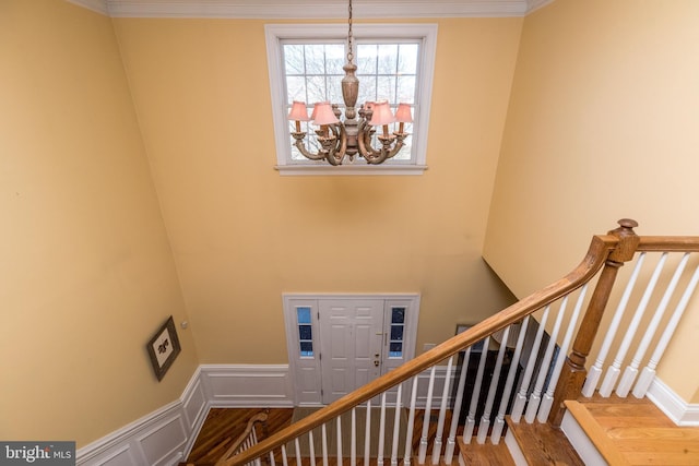 stairs featuring hardwood / wood-style floors, a notable chandelier, and crown molding