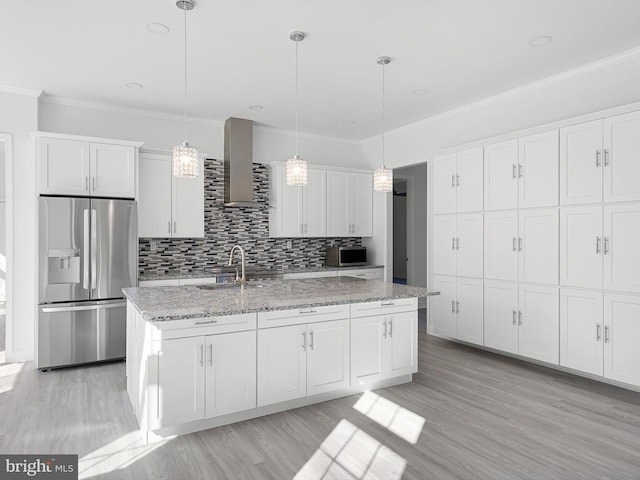 kitchen with wall chimney exhaust hood, appliances with stainless steel finishes, hanging light fixtures, and white cabinetry