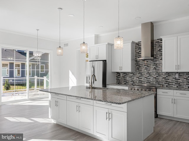 kitchen featuring wall chimney exhaust hood, white cabinets, and an island with sink