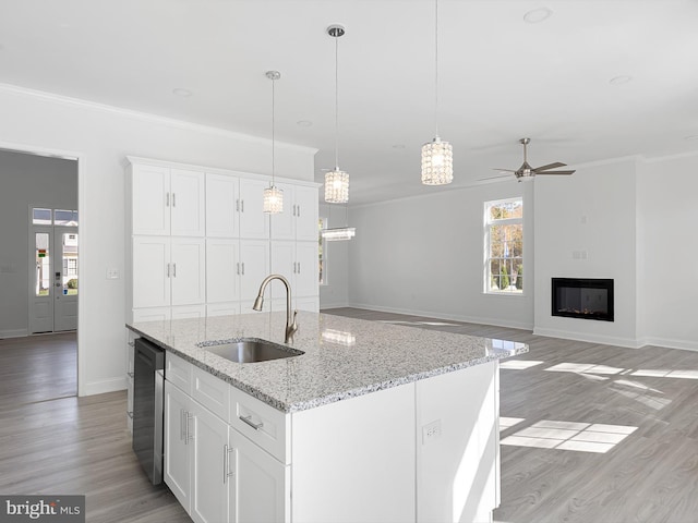 kitchen with light hardwood / wood-style flooring, white cabinetry, a kitchen island with sink, and sink