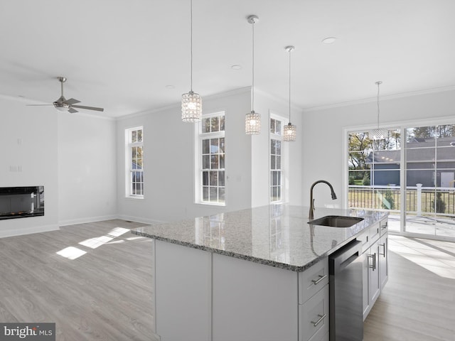 kitchen featuring light hardwood / wood-style floors, light stone countertops, sink, and decorative light fixtures