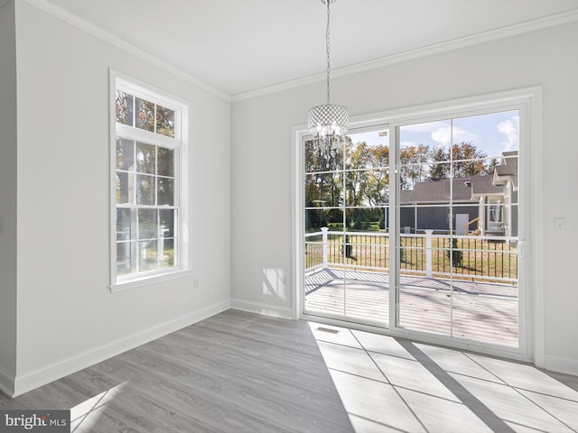 unfurnished dining area with light hardwood / wood-style floors, ornamental molding, and an inviting chandelier