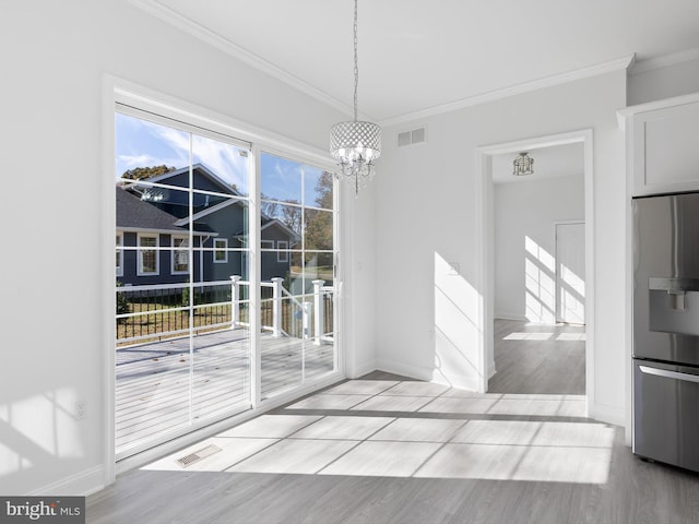 unfurnished dining area with light hardwood / wood-style flooring, a chandelier, and crown molding