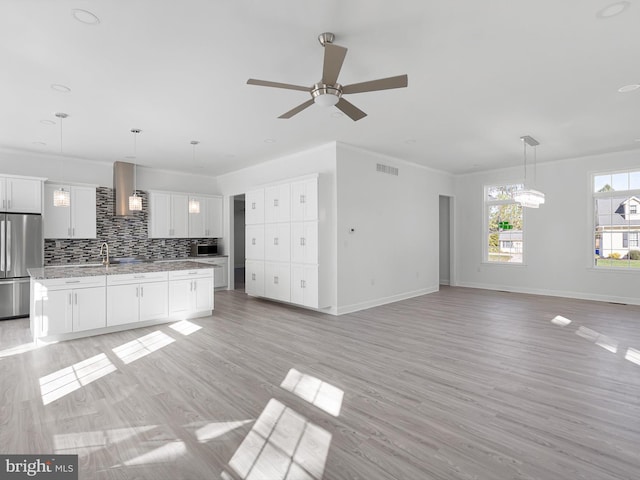 kitchen featuring appliances with stainless steel finishes, decorative light fixtures, white cabinets, and light hardwood / wood-style floors