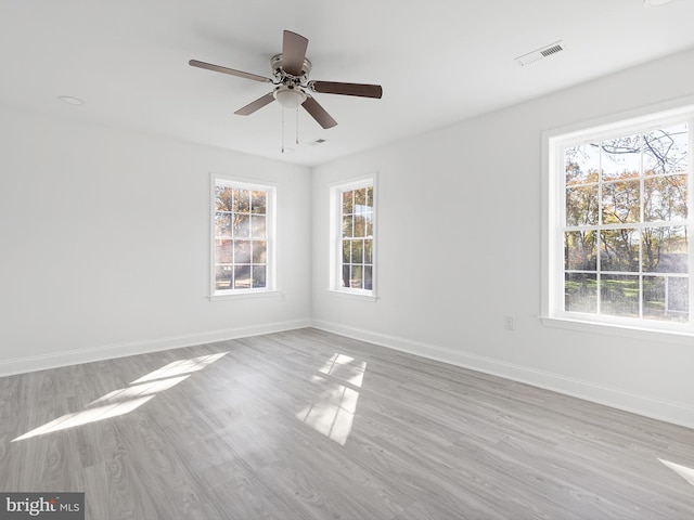 spare room with light wood-type flooring, plenty of natural light, and ceiling fan