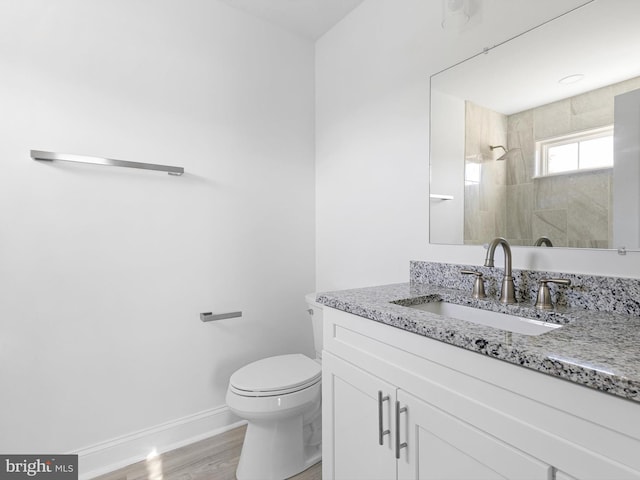 bathroom with vanity, tiled shower, hardwood / wood-style flooring, and toilet