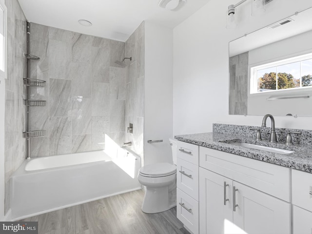 full bathroom with vanity, tiled shower / bath, toilet, and wood-type flooring