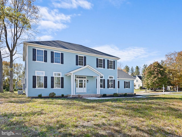 colonial home with a front yard and central AC unit