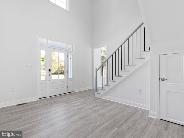 entryway featuring ornamental molding, a high ceiling, and light wood-type flooring