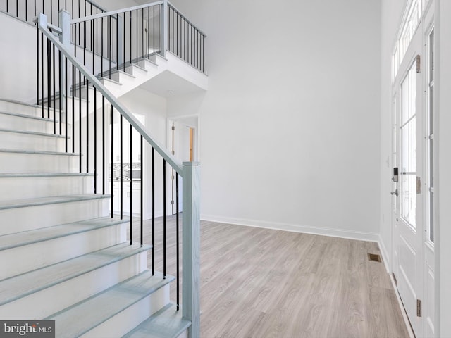 foyer entrance with light hardwood / wood-style flooring and a high ceiling