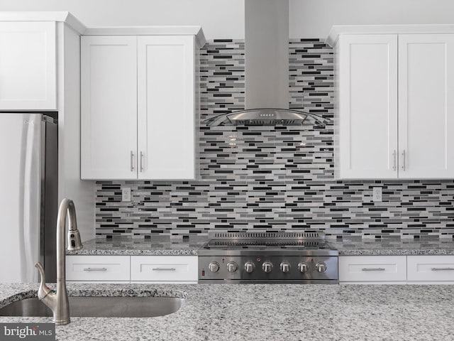 kitchen featuring decorative backsplash, white cabinetry, sink, wall chimney exhaust hood, and stainless steel appliances