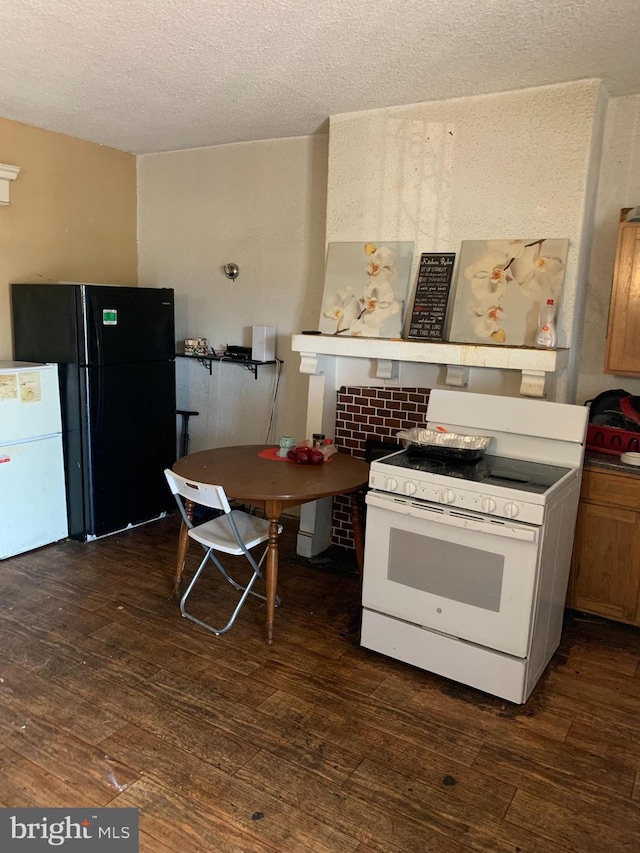 kitchen featuring dark hardwood / wood-style flooring, a textured ceiling, and white appliances