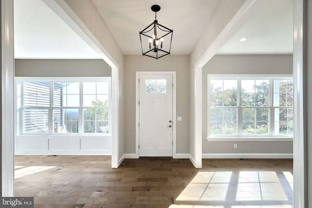 entryway featuring wood-type flooring, an inviting chandelier, and plenty of natural light