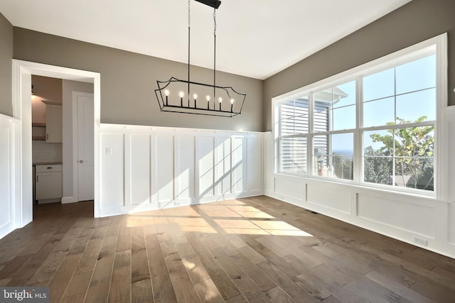 unfurnished dining area with a notable chandelier and wood-type flooring