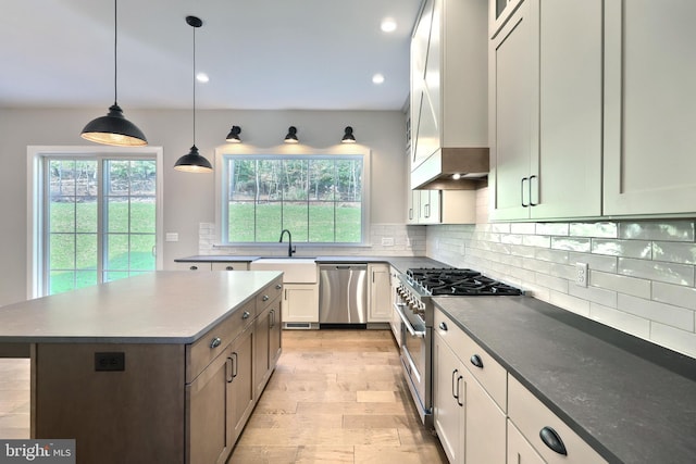 kitchen with appliances with stainless steel finishes, white cabinets, plenty of natural light, and a kitchen island