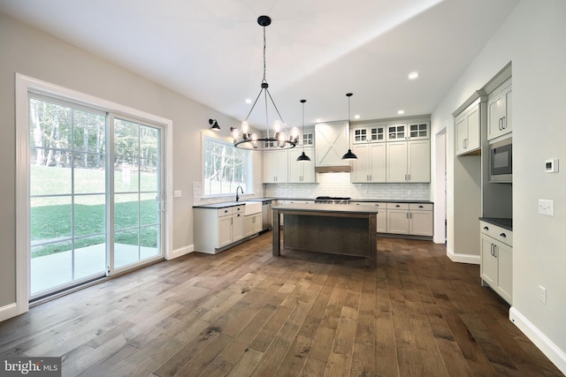 kitchen with an inviting chandelier, a center island, dark wood-type flooring, sink, and decorative light fixtures