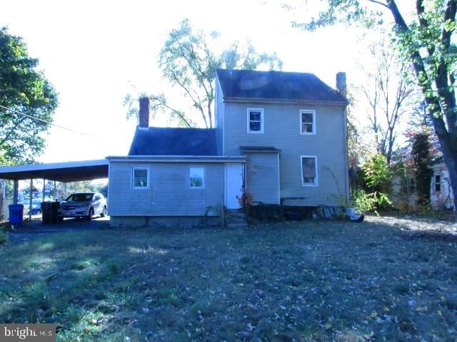 rear view of property featuring a lawn and a carport