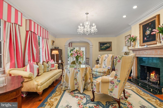 living room featuring a fireplace, wood-type flooring, an inviting chandelier, and ornamental molding