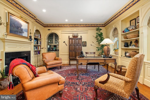 office area with built in features, light hardwood / wood-style floors, and ornamental molding