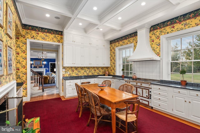 kitchen featuring coffered ceiling, white dishwasher, custom range hood, beamed ceiling, and white cabinetry