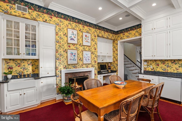 dining space with coffered ceiling, crown molding, sink, beam ceiling, and a fireplace