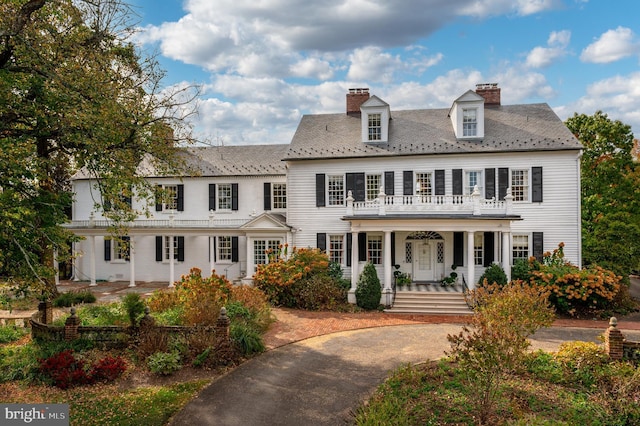 colonial-style house featuring a balcony and covered porch