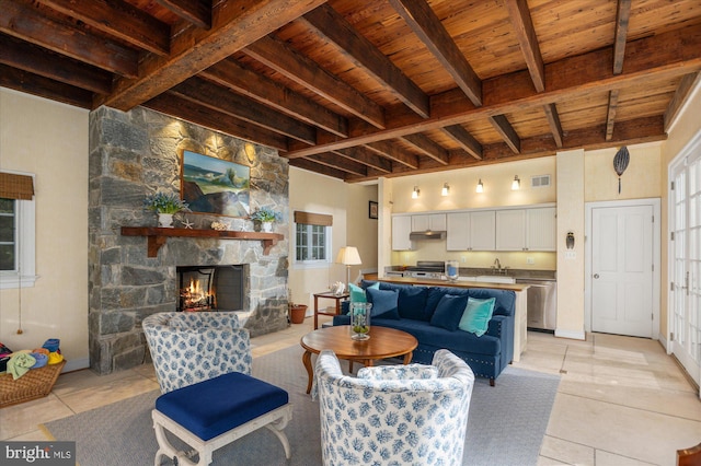 living room featuring beam ceiling, wood ceiling, a fireplace, and light tile patterned floors