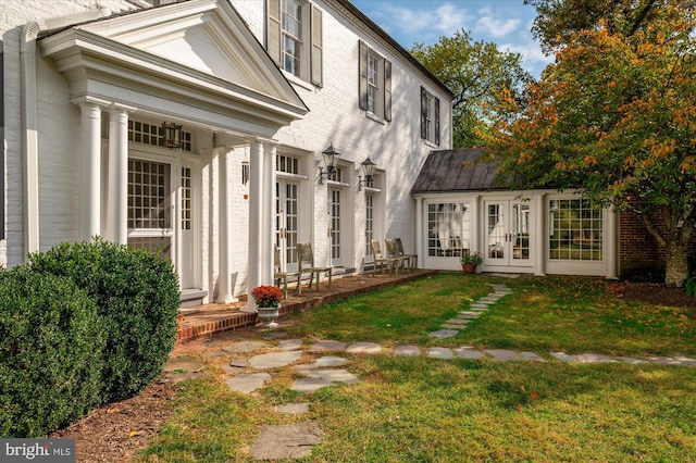 back of property with a lawn and french doors